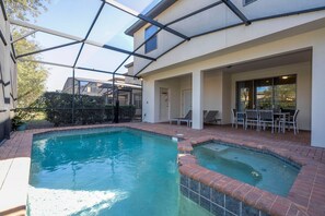 A residential swimming pool with a glass-enclosed patio area, a small deck, and a seating arrangement. - 6BR near Disney | Private pool, spa, movie room (Kissimmee)