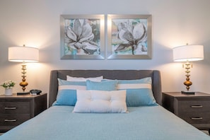 A bedroom with a bed, two nightstands, two lamps, and two framed floral artworks on the wall. - 6BR near Disney | Private pool, spa, movie room (Kissimmee)