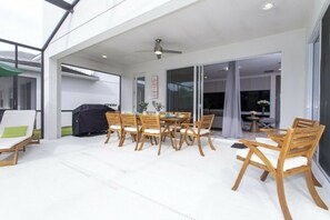 An outdoor patio with a dining table and chairs, a grill, and a ceiling fan. - 6BR near Disney | Pool, spa, Mickey & Marvel (Kissimmee)