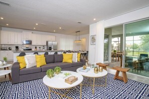 A modern apartment with a living room, kitchen, and balcony. - 6BR Solara Resort | Pool, spa & game room (Kissimmee)