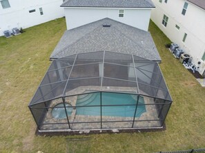 Ein Garten mit Zaun und Schwimmbad, umgeben von einem weißen Gebäude mit vielen Fenstern.