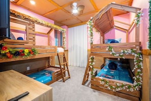 Ein Zimmer mit Etagenbetten, einem Holztisch und einem Deckenventilator.