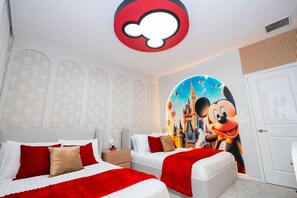 Ein Hotelzimmer mit zwei Betten, einem großen Disney-Wandbild und einer ungewöhnlichen, runden Leuchte.