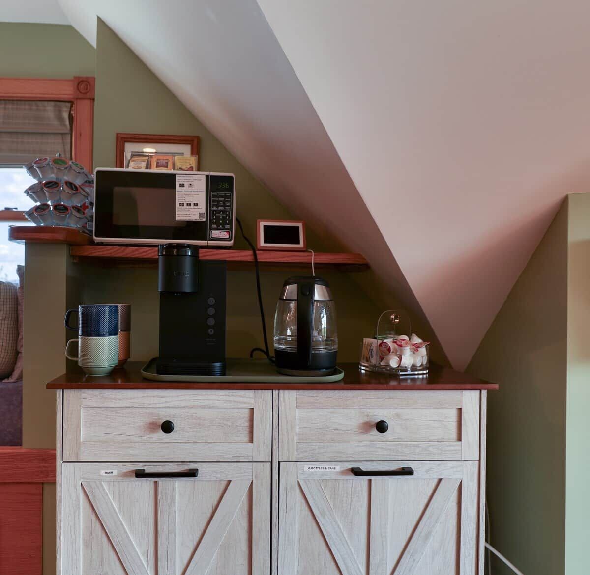 A kitchenette with a coffee maker, microwave, and a small digital clock on a wooden cabinet.