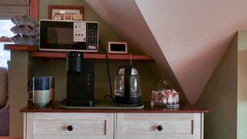 A kitchenette with a coffee maker, microwave, and a small digital clock on a wooden cabinet.