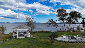 A gazebo with a patio, overlooking a lake with boats, trees, and distant mountains. - Peaceful Loft with Gazebo and Firepit (Surry)