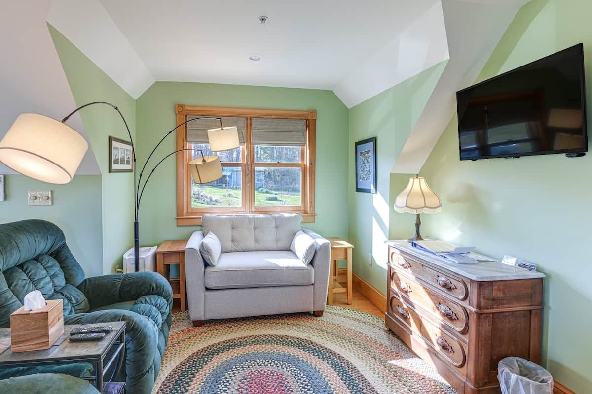 A living room with a sofa, a loveseat, a coffee table, a lamp, a TV, a window, and a dresser.