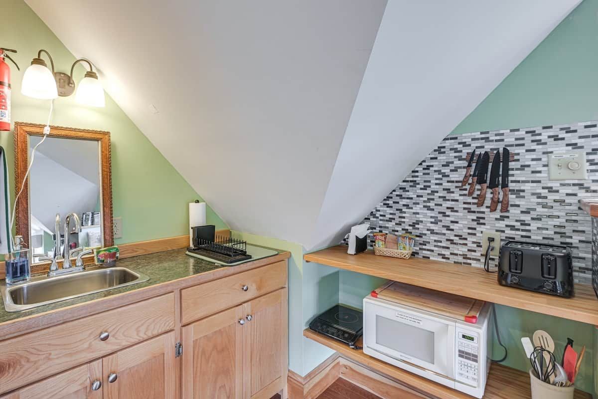 A kitchen with a sink, a microwave, a toaster, and a mirror.