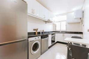 Eine moderne Küche mit Edelstahlgeräten, einer integrierten Waschmaschine und einem Essbereich mit Tisch und Stühlen.