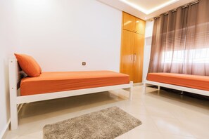 Ein Schlafzimmer mit zwei Einzelbetten, einem Holzschrank und einem Fenster mit Vorhängen.