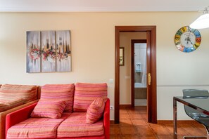 A living room with a sofa, a painting, a clock, and a door leading to a bathroom. - Apartment 'a pie de playa en Ris' (Noja)