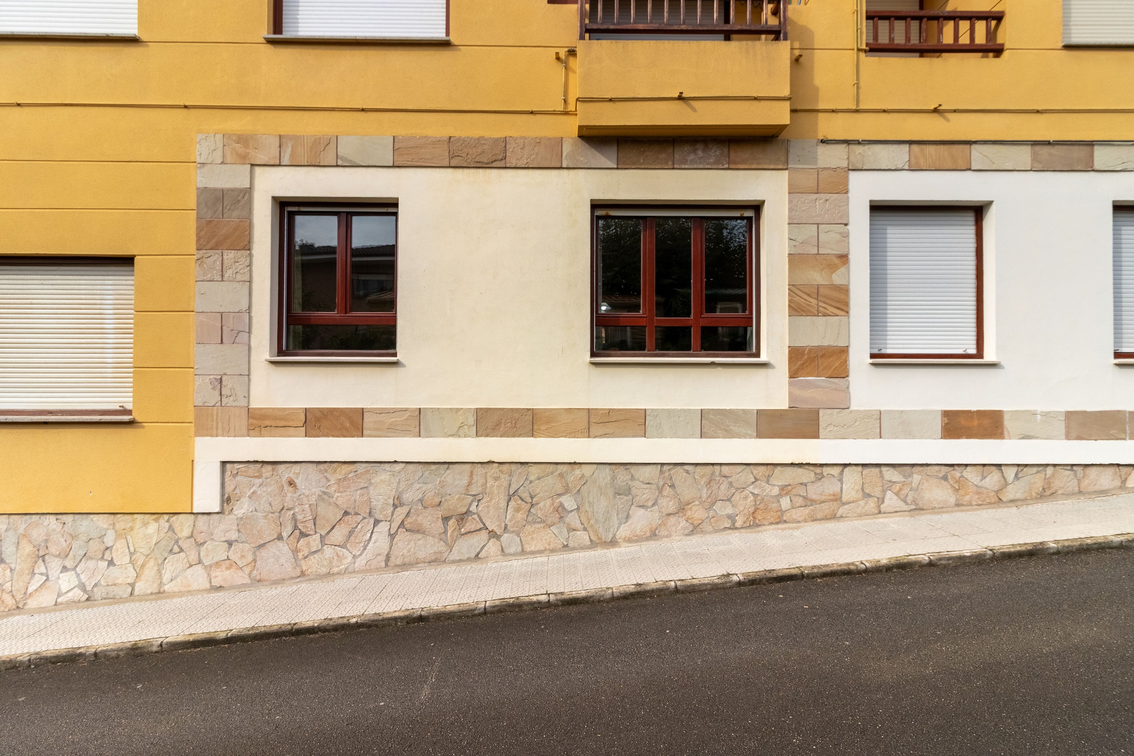 Fachada de edificio con tres ventanas, cada una con un estilo de persiana diferente.