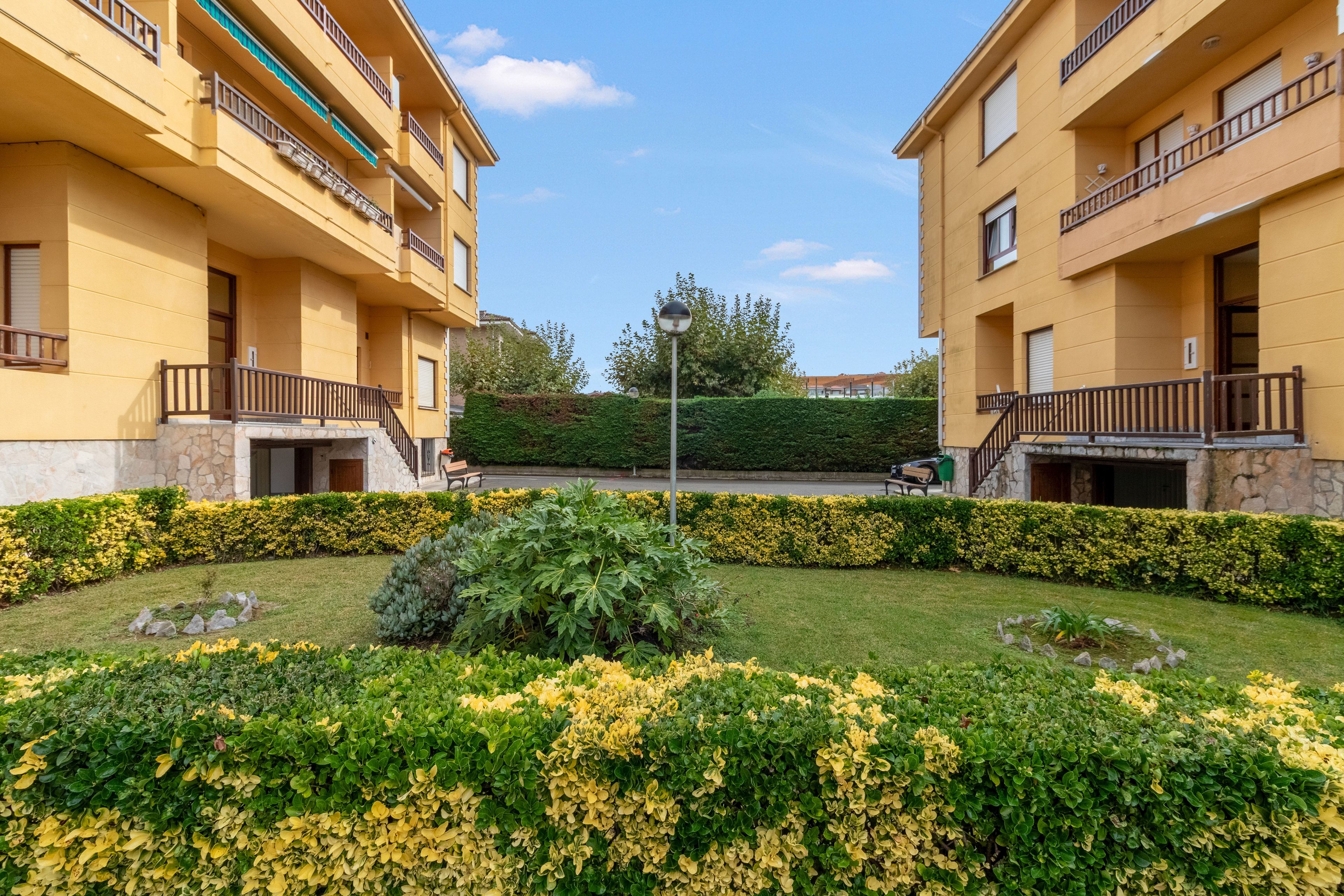 Un cortile con un'area verde centrale, circondato da edifici gialli con balconi.