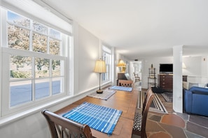 A dining area with a wooden table, blue placemats, and a lamp. - The Village Anchor/Cozy Flat near Harbor & Shops (Rockport)
