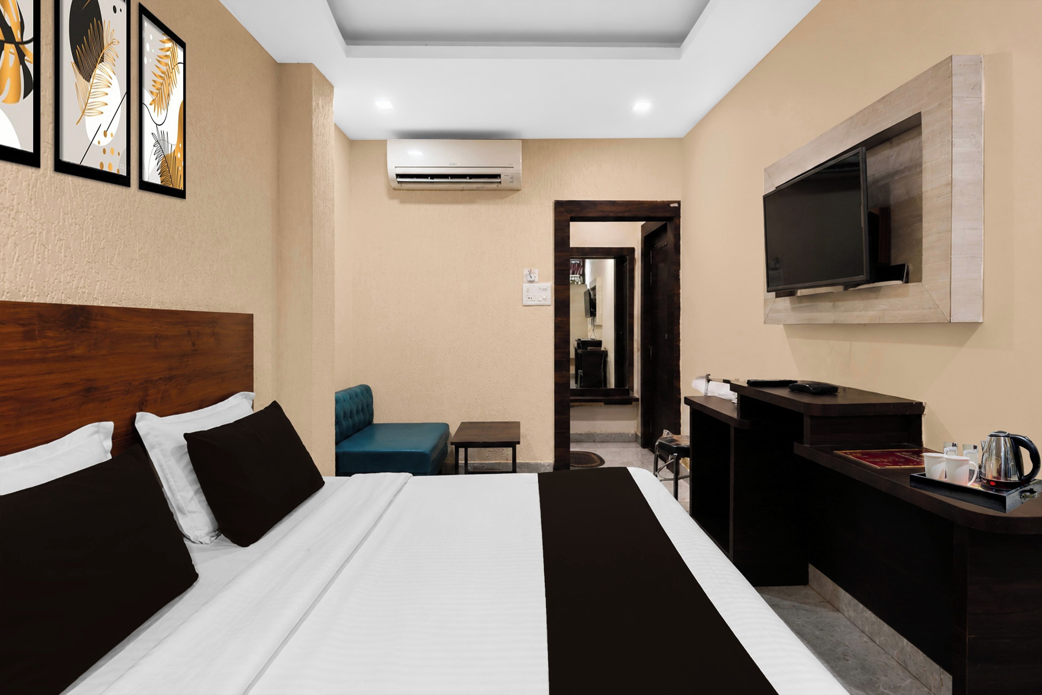 Een hotelkamer met een bed, een bureau, een stoel, een televisie en een airconditioning.