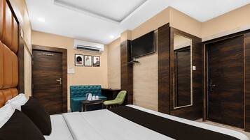 A hotel room with a bed, a seating area with a table, a TV mounted on the wall, and a wardrobe.