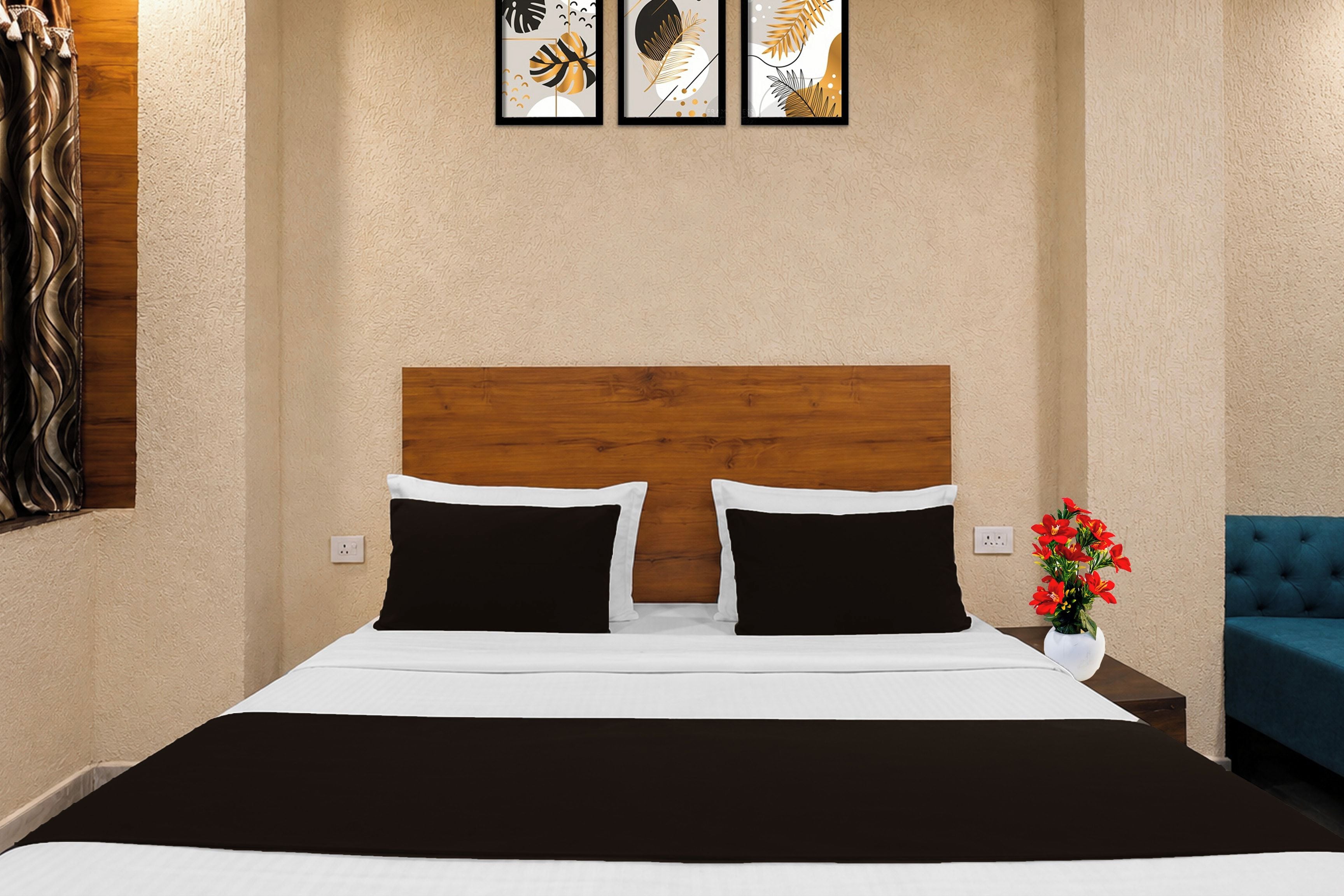 Ein Hotelzimmer mit Bett, Nachttisch, Blumen in einer Vase und einem blauen Sessel.
