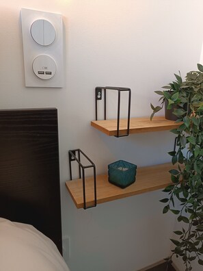 A bedroom with a bed, a wall-mounted power outlet, and a potted plant. - Studio 'Le Cocoon des Rives' at the gates of Roanne (Commelle-Vernay)