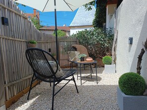 A patio with a black metal chair, a small round table, and a white umbrella. - Studio 'Le Cocoon des Rives' at the gates of Roanne (Commelle-Vernay)