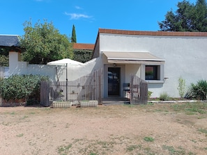 A single-story building with a white exterior, a covered patio area, and a fenced garden. - Studio 'Le Cocoon des Rives' at the gates of Roanne (Commelle-Vernay)