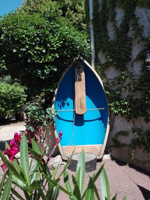 A wooden boat-shaped structure with a rope tied to it, surrounded by greenery and a stone wall. - Studio 'Le Cocoon des Rives' at the gates of Roanne (Commelle-Vernay)