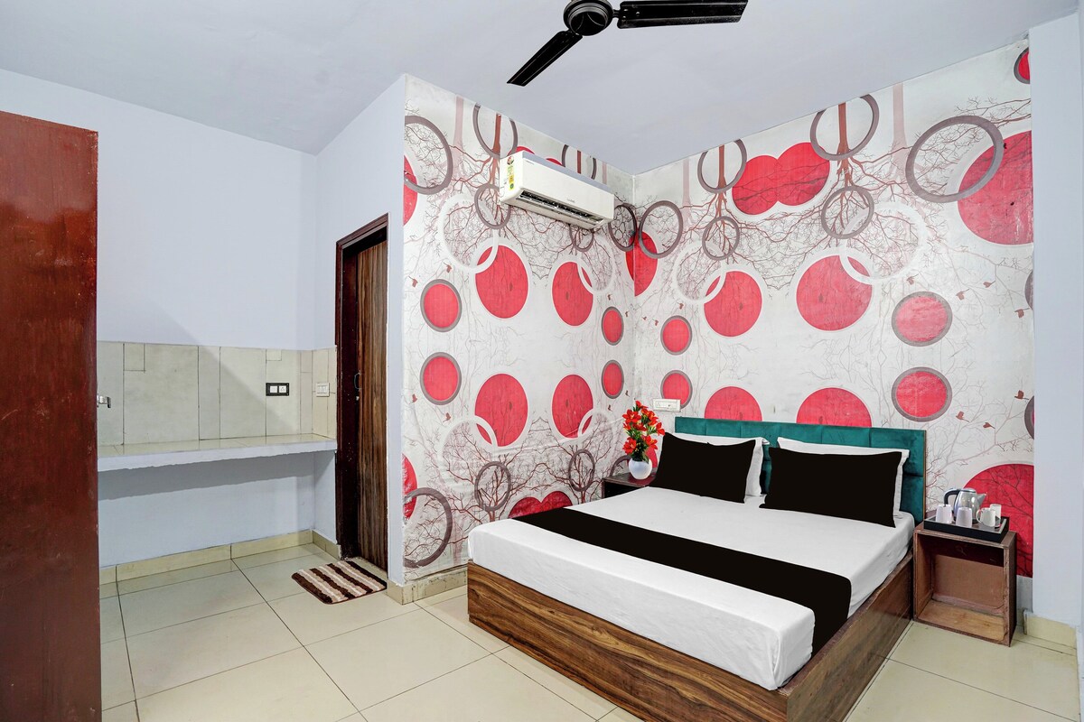 Un dormitorio con una cama, una mesita de noche, aire acondicionado de pared y una puerta.