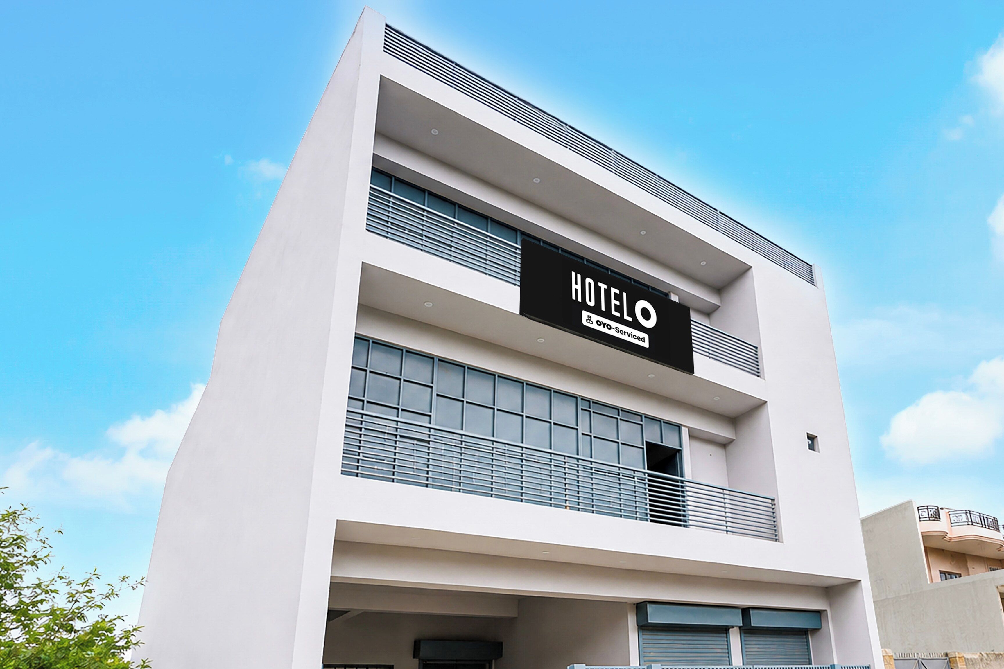 A modern hotel building with a prominent sign reading 'HOTEL' and 'Oyo-Serviced'.