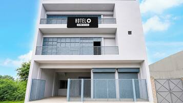 Un moderno edificio de hotel con un cartel que dice 'HOTEL OYO-Serviced' y una entrada con rejas.