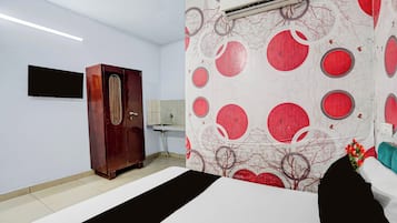 Una habitación de hotel con cama, armario, lavabo y aire acondicionado instalado en la pared.