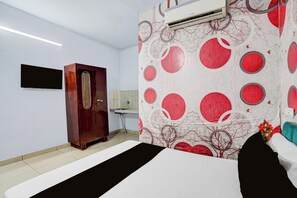 Una habitación de hotel con cama, armario, lavabo y aire acondicionado instalado en la pared.
