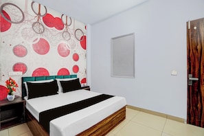 A bedroom with a bed, a wall with a circular pattern, a door, and a nightstand with a vase of flowers. - Hotel O Threeke Highway Ludhiana (Ludhiana)