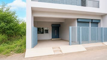 A modern two-story building with a flat roof, a covered entrance, and a gated driveway.