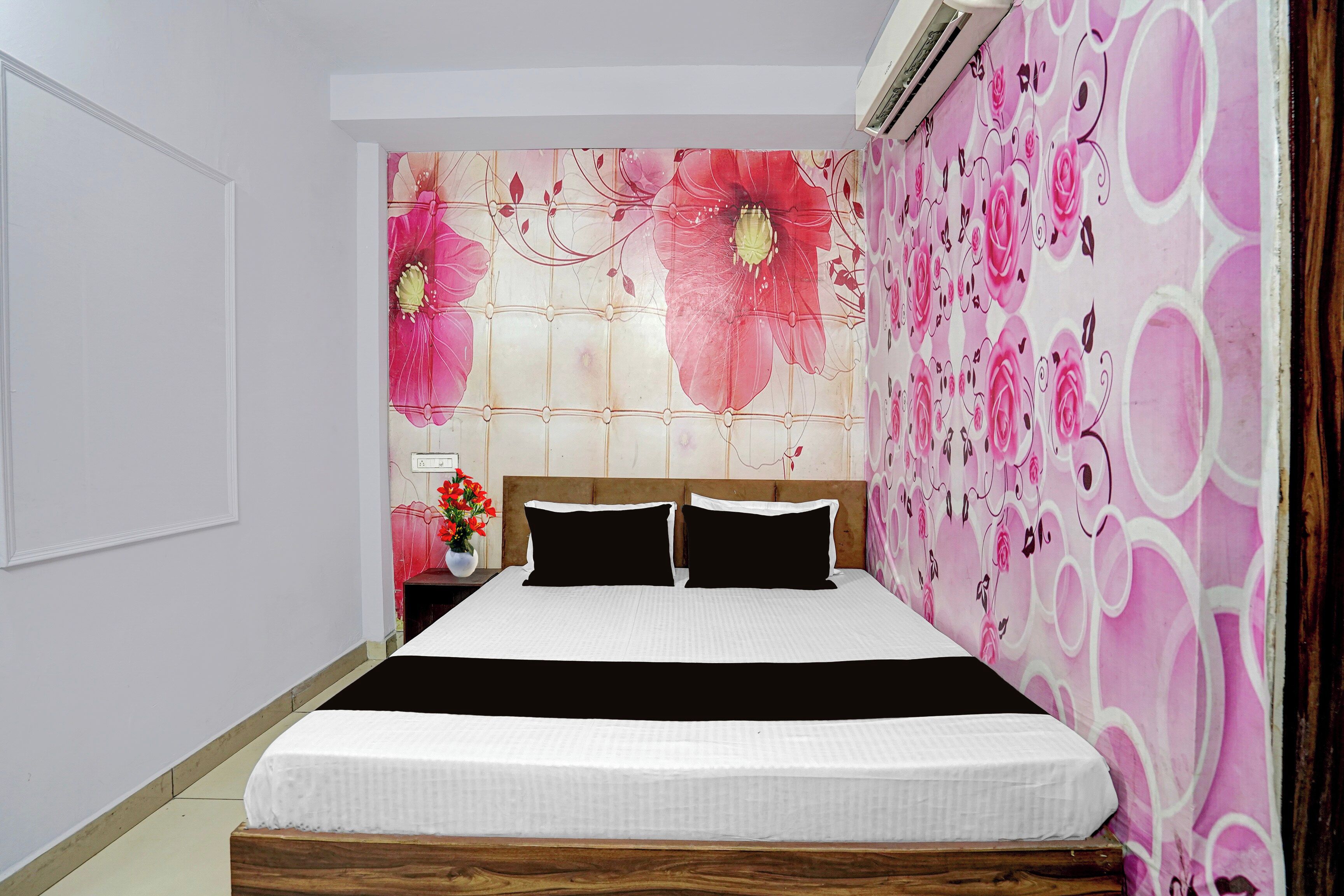 Un dormitorio con cama, mesita de noche y pared con estampado floral.