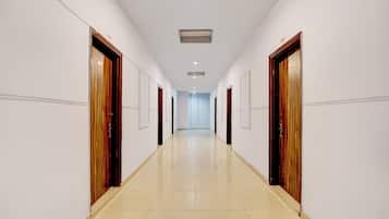 A long, narrow hallway with doors on both sides, leading to a bright room at the end.