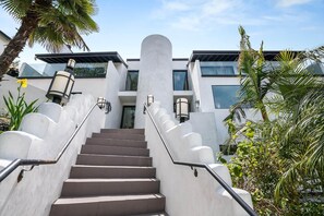 Un escalier menant à un bâtiment à l’architecture moderne, caractérisé par une façade blanche et une série de marches dotées de rampes.