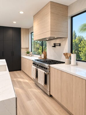 Une cuisine moderne dotée d’une grande fenêtre, d’un four encastré et de meubles de rangement en bois.