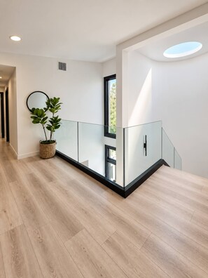 Ein modernes Interieur mit Holzboden, Glastrennwand und einer Kühlpflanze.