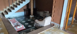 A room with a staircase, a sofa, a small table, and a cabinet. - Eco-friendly 2-bedroom house with mountain view in charming Thenkarai with AC (Thenkarai)