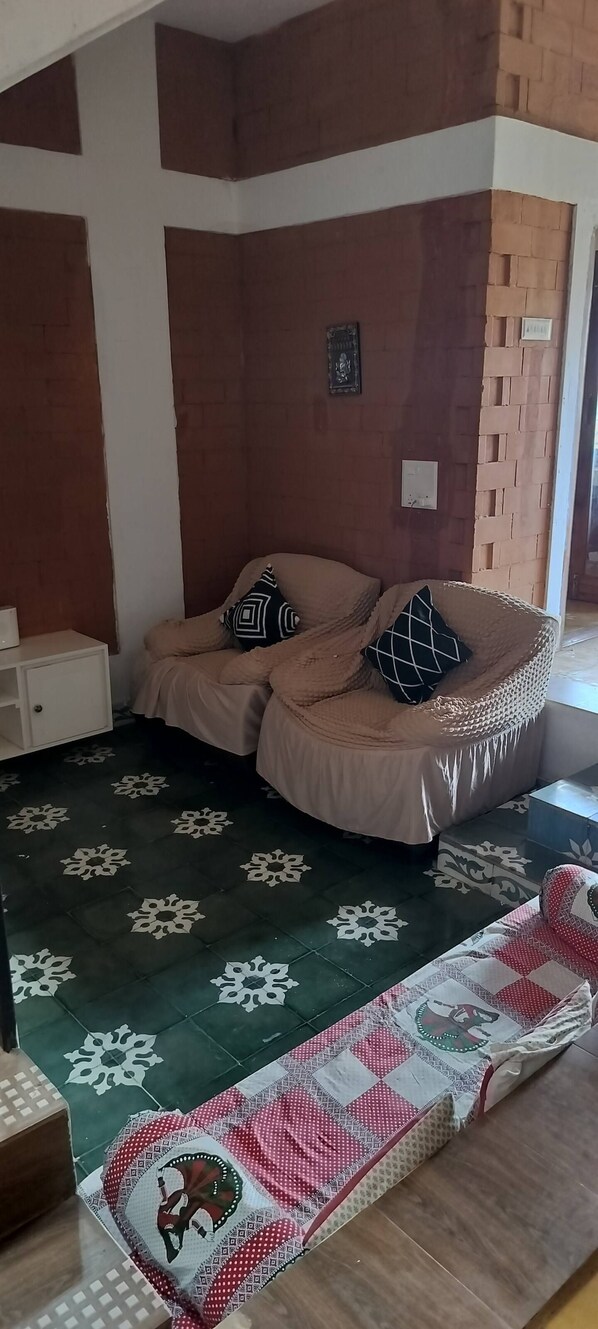 A bedroom with a bed, a nightstand, a decorative rug, and a wall-mounted light switch. - Eco-friendly 2-bedroom house with mountain view in charming Thenkarai with AC (Thenkarai)