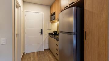 Una cocina compacta con refrigerador empotrado, armarios de madera y microondas.
