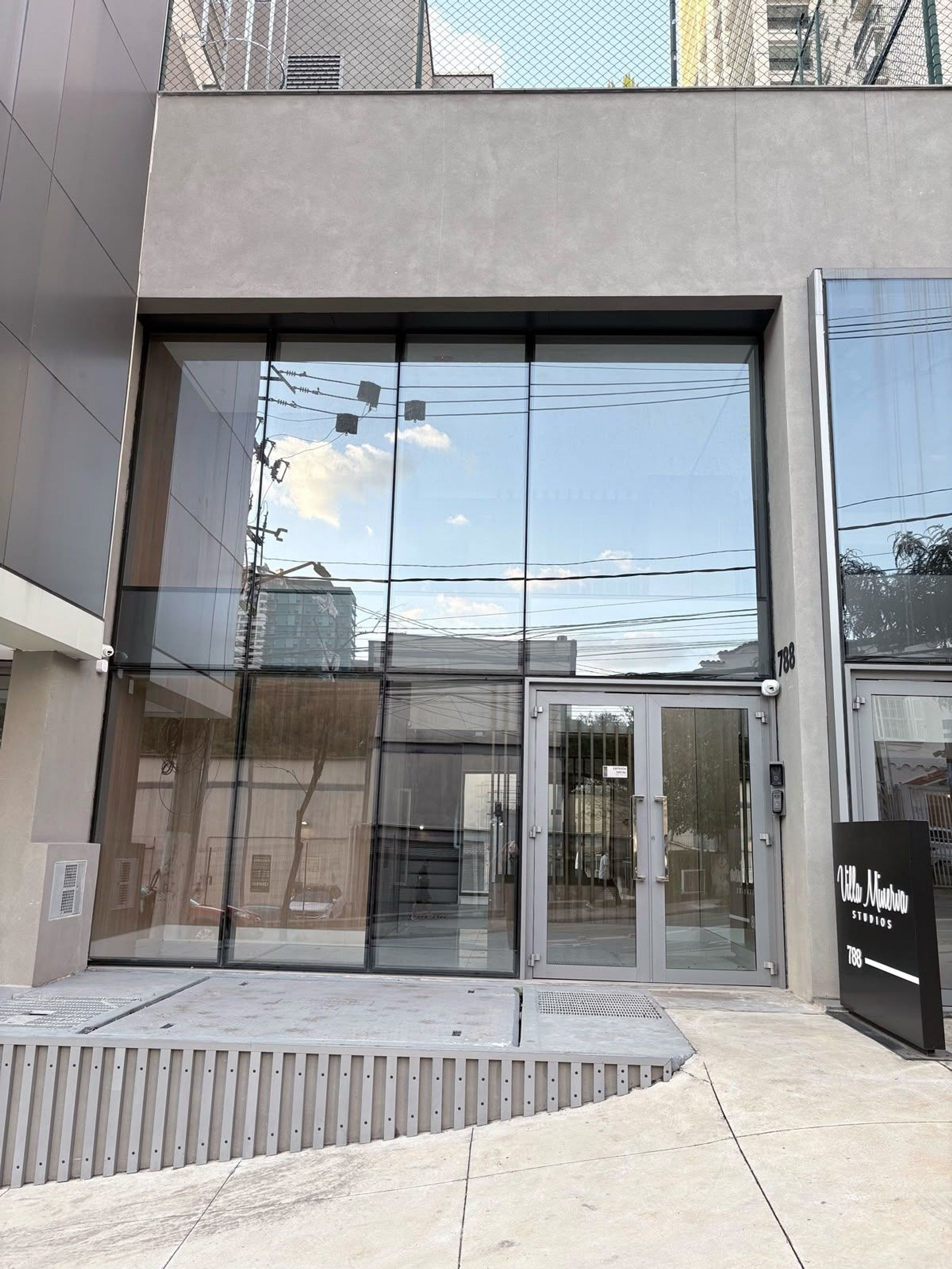 Een modern gebouw met grote glasramen en een metalen hek.