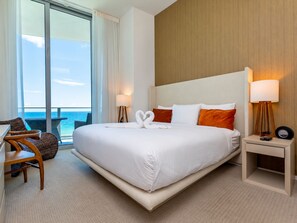 A hotel room with a large bed, a desk, a chair, a nightstand, and a view of the ocean. - Panoramic Ocean View Entire Rental Unit - 2bed/2bath Hotel Suite, Hollywood, FL (Hollywood)