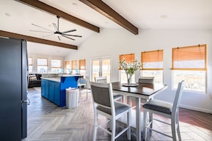 A spacious kitchen with a central island, wooden herringbone flooring, and a dining area with a table and chairs. - AEA- Crystal Beach (Bolivar Peninsula)