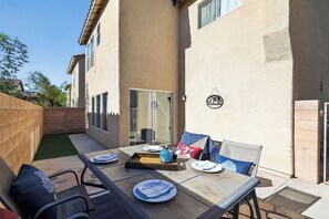 An outdoor patio with a table set for dining, a chair, and a small garden area. - 3BR Home Near Las Vegas Strip I Mid-Term Stays (Las Vegas)