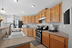 A modern kitchen with wooden cabinets, stainless steel appliances, and a built-in oven. - 3BR Home Near Las Vegas Strip I Mid-Term Stays (Las Vegas)