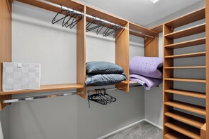 A walk-in closet with wooden shelving, a hanging rod, and a folded purple garment. - 3BR Home Near Las Vegas Strip I Mid-Term Stays (Las Vegas)