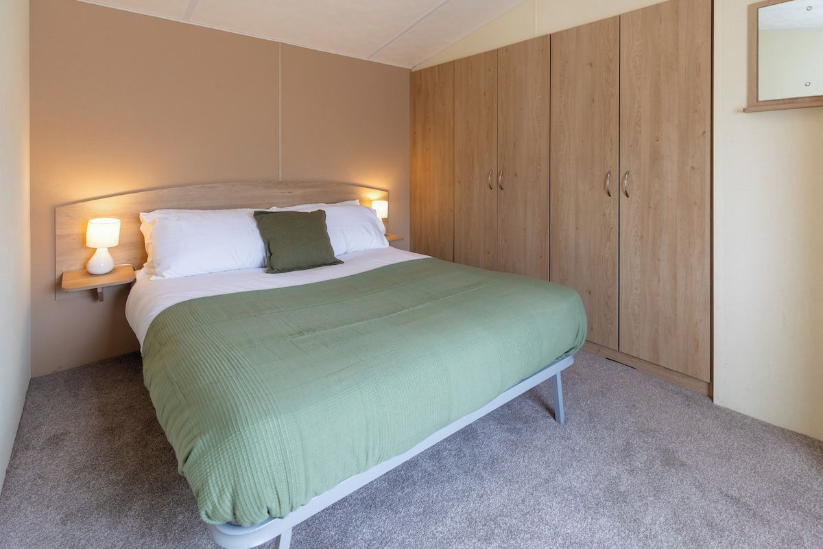 A bedroom with a bed, a nightstand, a lamp, and a wardrobe.