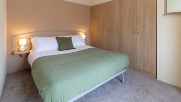 A bedroom with a bed, a nightstand, a lamp, and a wardrobe.