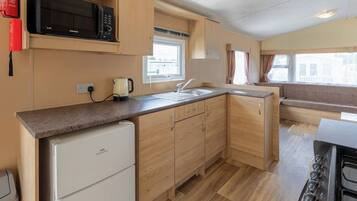 A compact kitchen with a microwave, a coffee maker, and a stove.