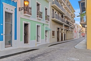 Une rue étroite bordée de bâtiments aux couleurs vives, chacun doté de balcons et de fenêtres.
